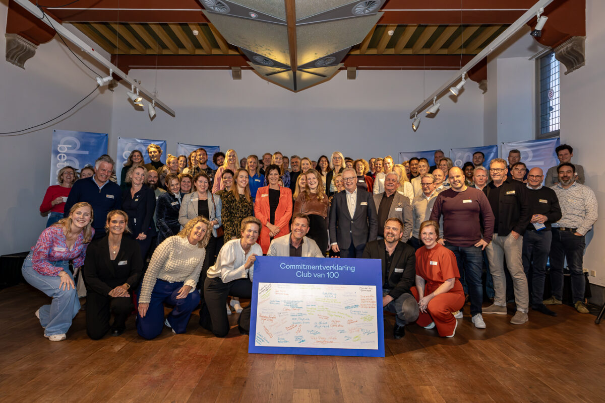 De 100 leden van de club van 100 van de Friese Merkpositionering staan gezamenlijk op de foto. Op de voorgrond staat een grote symbolische verklaring met daarop de handtekening van alle deelnemers.
